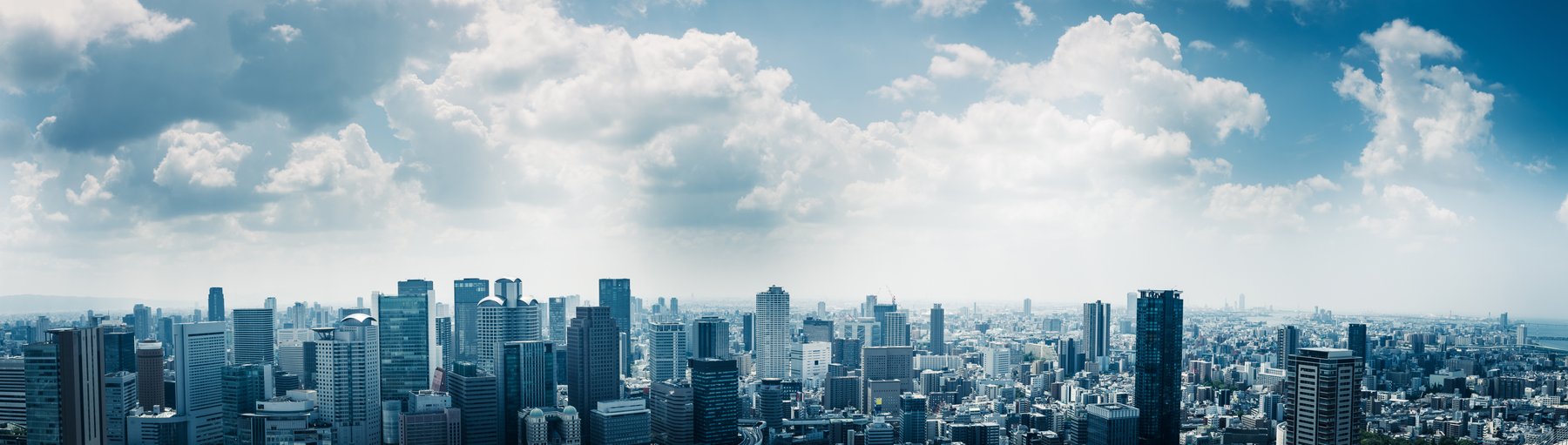 青空と雲の下に広がる都市のビル群
