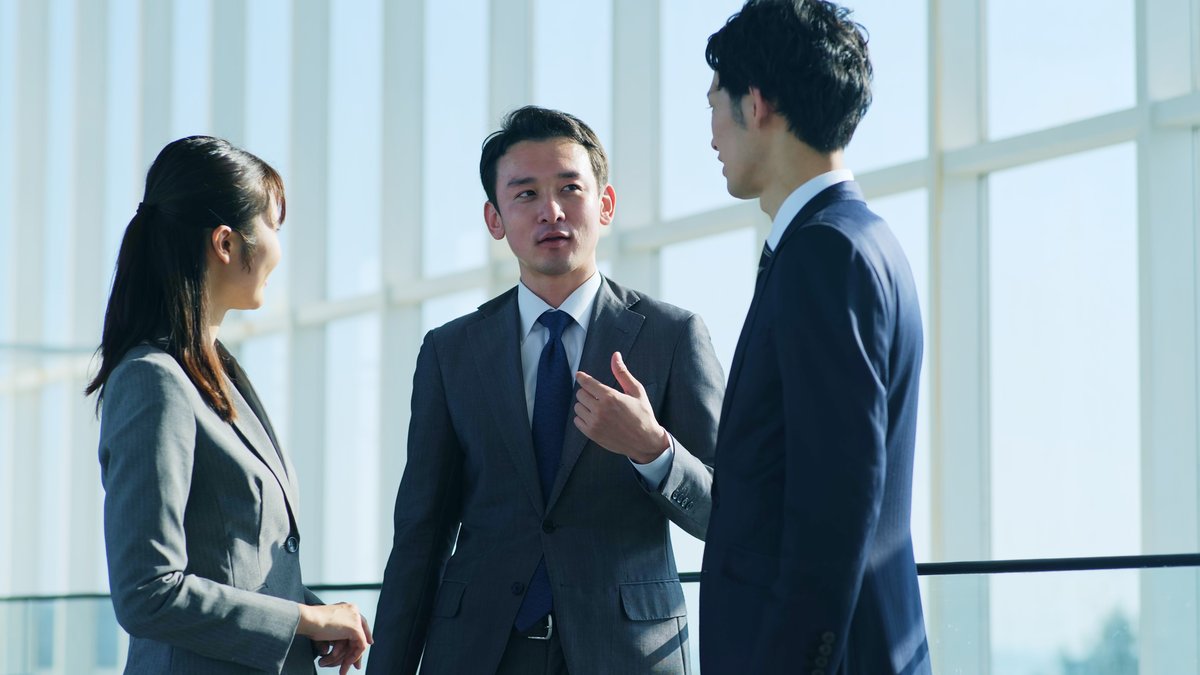 オフィスで語り合う3人のビジネスパーソン